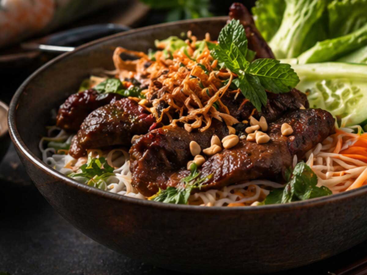 Vietnamesische Reisnudel-Bowl mit Fleisch, Salat, Kräutern und Erdnüssen